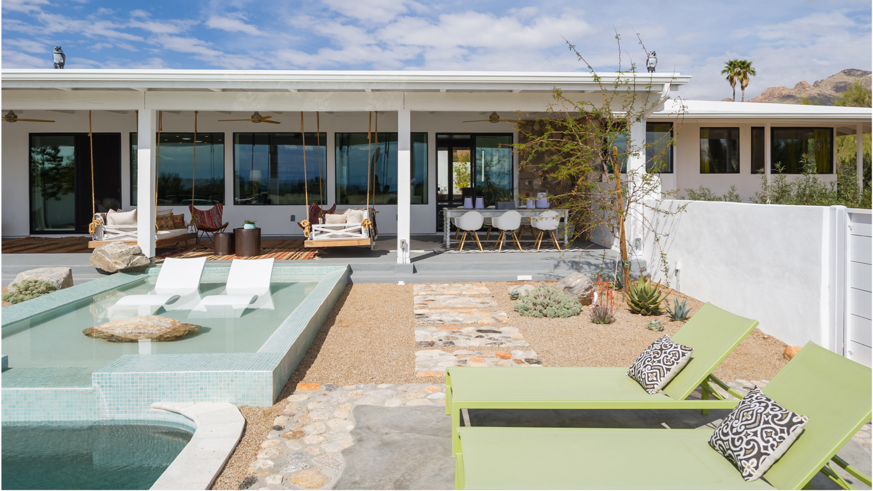 Two green chaise loungers and two white in pool loungers give ample relaxation options to this modern pool deck. 