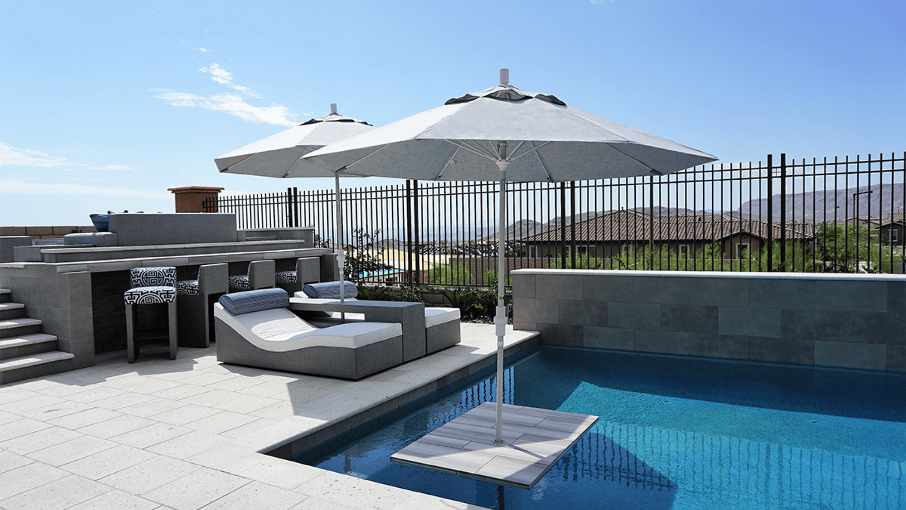 Two parasol outdoor umbrellas shade a pool lounge area.