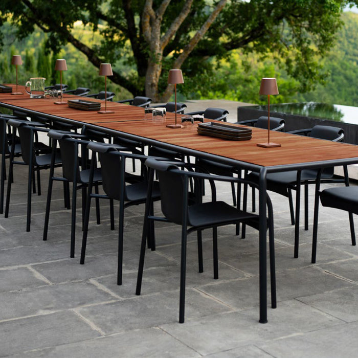 A long banquet table with dark wood top and black metal frame accompanied by matching black metal round-back chairs.