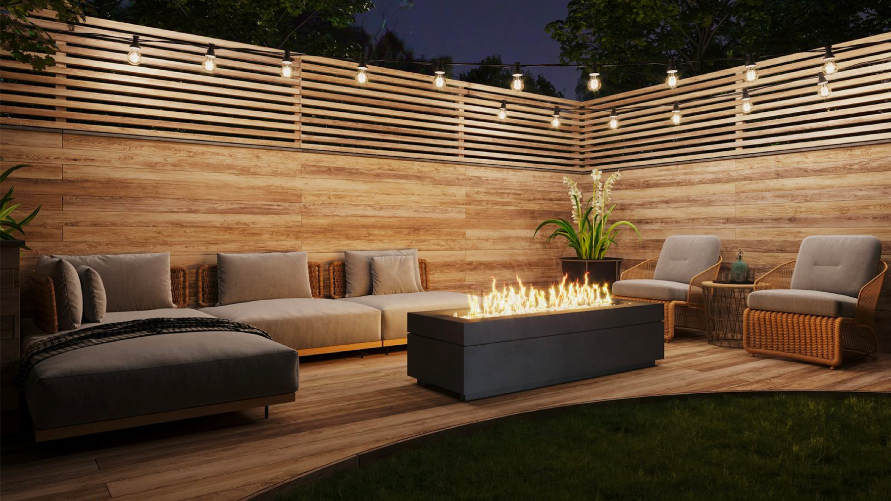 Boxhill's Linea fire pit burns bright as the centerpiece on a backyard deck with wooden privacy wall and string lights.