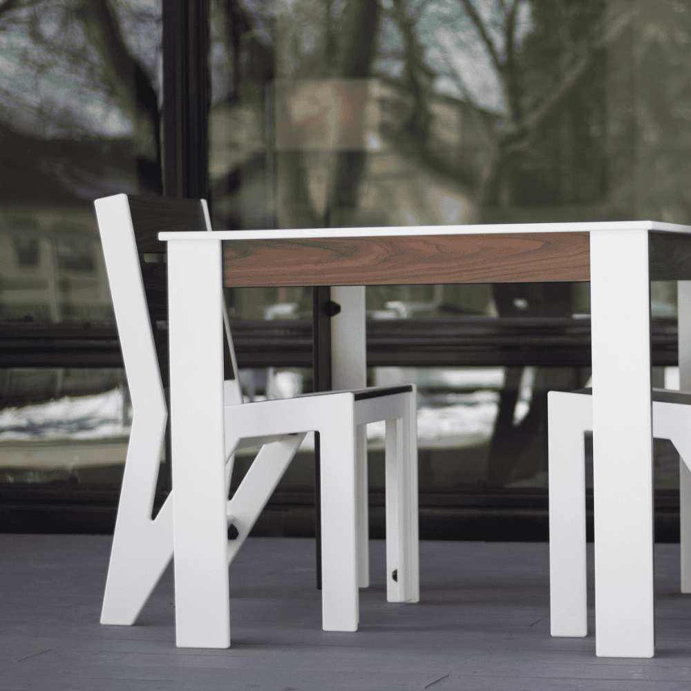 White outdoor dining chair with dark gray wood grain back rest and seat and a white square dining table set on a patio beside glass wall