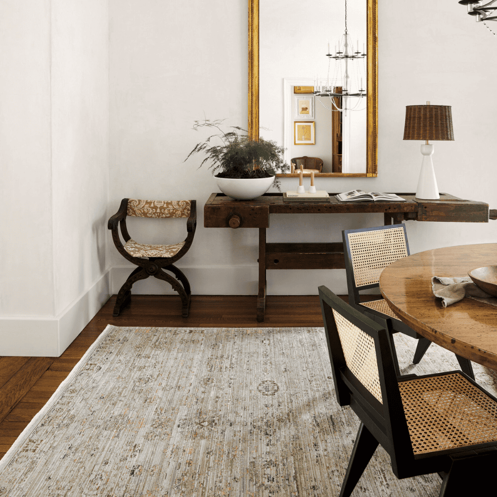 A Light brown machine woven outdoor rug with geometric pattern on an indoor setting with round wooden dining table and chairs