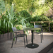 2 black stackable outdoor dining chair and a black round outdoor dining table placed on a patio surrounded by plants