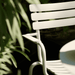 Close up view of a white stackable outdoor dining chair beside plants