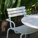 A white stackable outdoor dining chair set on a patio beside white round outdoor dining table