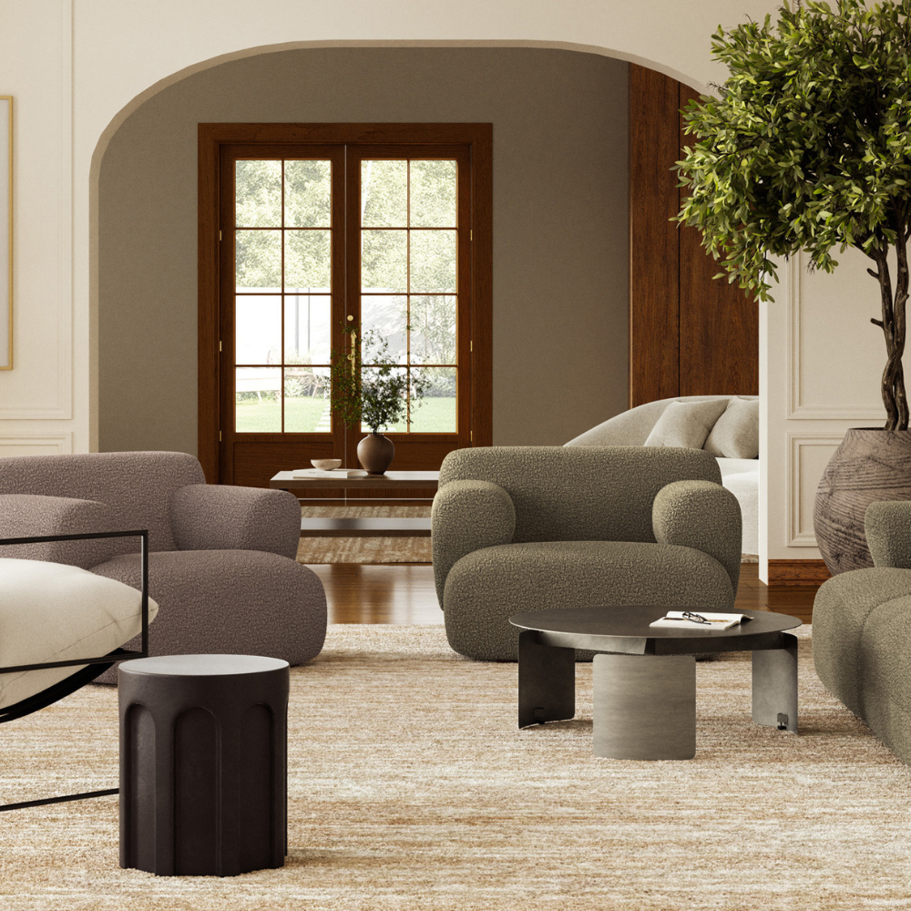 A round outdoor concrete round stool in matte black color placed in a modern living room set up accompanied by sofa and lounge chairs