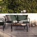 A wooden outdoor lounge table with black metal frame and dark green outdoor lounge sofa and chair set on a tiled patio