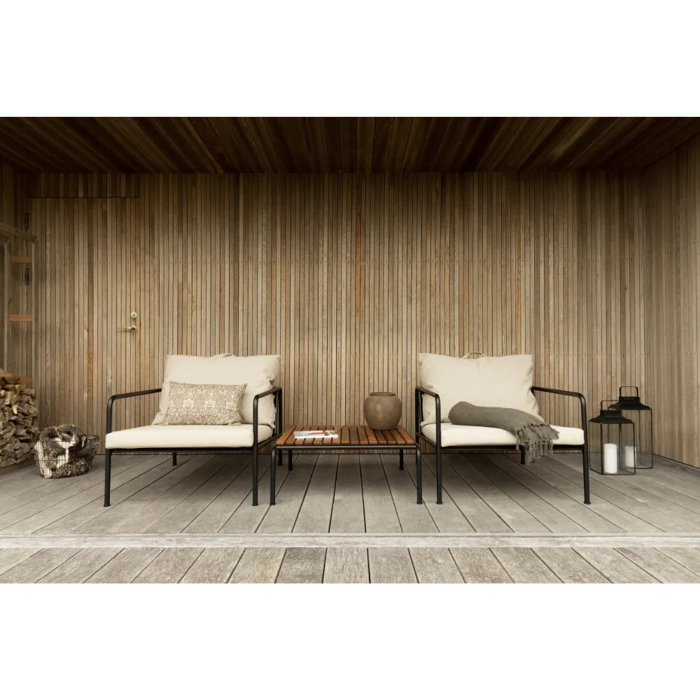 A wooden outdoor lounge table with black metal frame and 2 beige outdoor lounge chairs set on a wooden deck patio