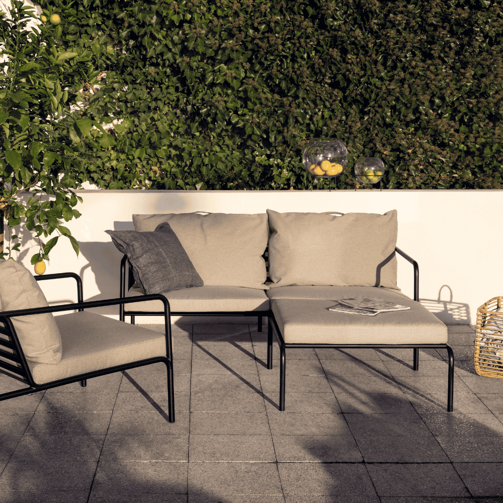 An outdoor patio with beige outdoor ottoman, outdoor 2-seater lounge sofa and outdoor lounge chair with black aluminum frame