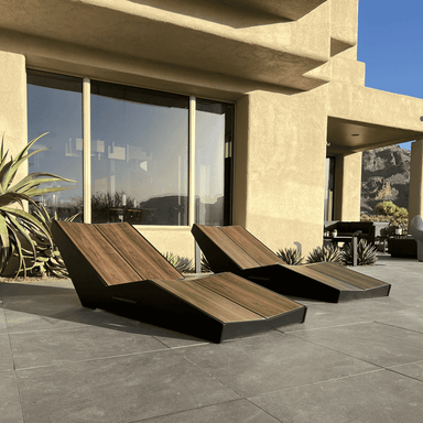 Two black outdoor chaise lounge with dark brown wood grain backrest placed on an outdoor patio near glass windows