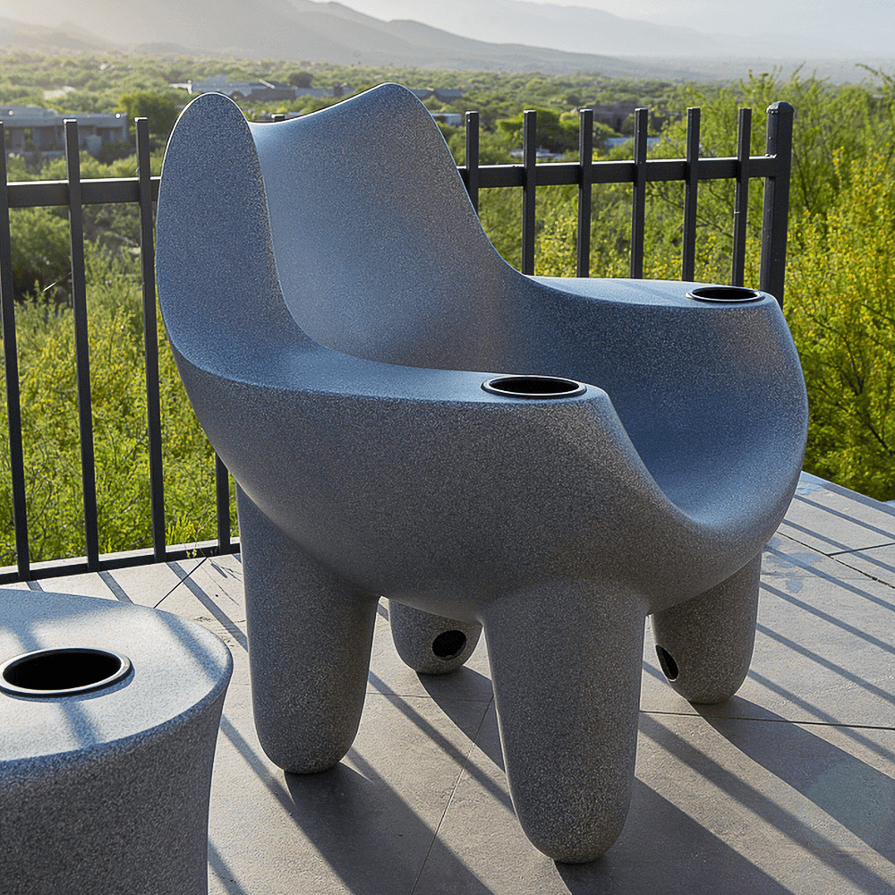 A grey pool chair placed against railing beside grassy field with a mountain backdrop