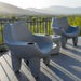 Two grey pool chairs on an outdoor space beside grassy field with a beautiful mountain backdrop