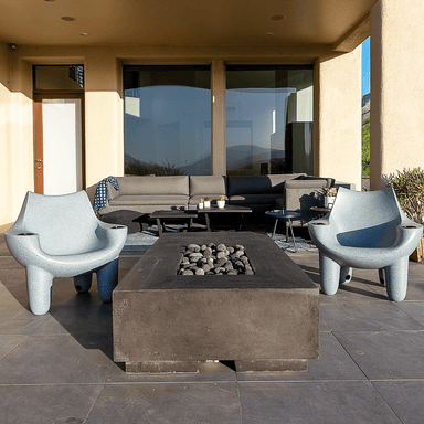 Outdoor patio with two grey pool chairs and a concrete fire table at the center