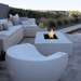 White concrete rectangular fire pit on a patio beside the pool with L shaped white sofa and a white moon shaped pool chair