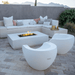 White concrete rectangular fire pit on a patio surrounded by L shaped white sofa and a white moon shaped pool chair