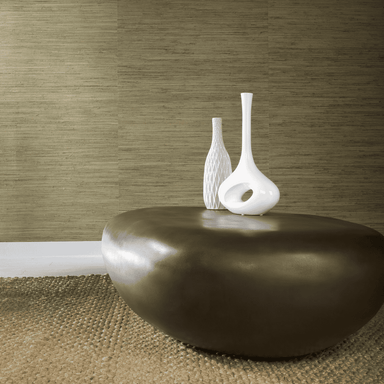 Bronze pebble coffee table with two white vases on it is placed on a brown rug near brown wall