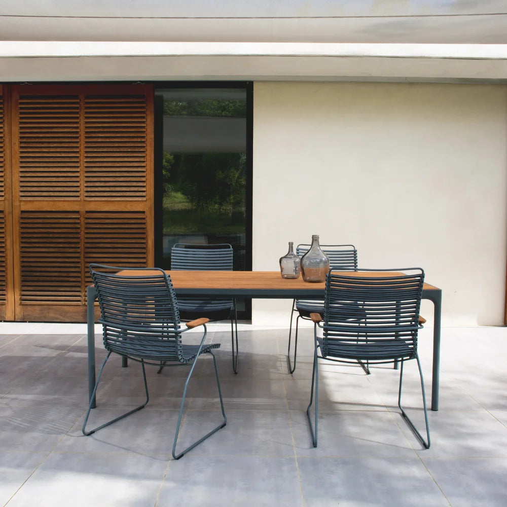 4 dark gray outdoor dining chair tall back and a wooden rectangular outdoor dining table with gray metal frame set on a patio