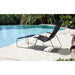 A black outdoor lounge chair with bamboo armrest and a black outdoor footrest placed beside the pool