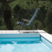 A dark blue outdoor lounge chair with bamboo armrest placed beside the pool