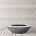 Grey outdoor round concrete fire bowl placed on a wooden deck against white brick wall