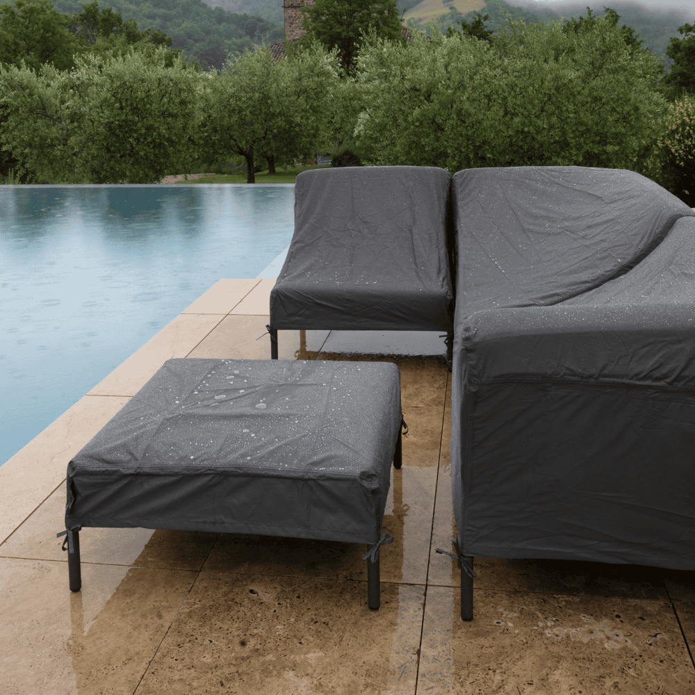 A poolside area with set of sofa and chairs covered by dark gray patio seat covers 