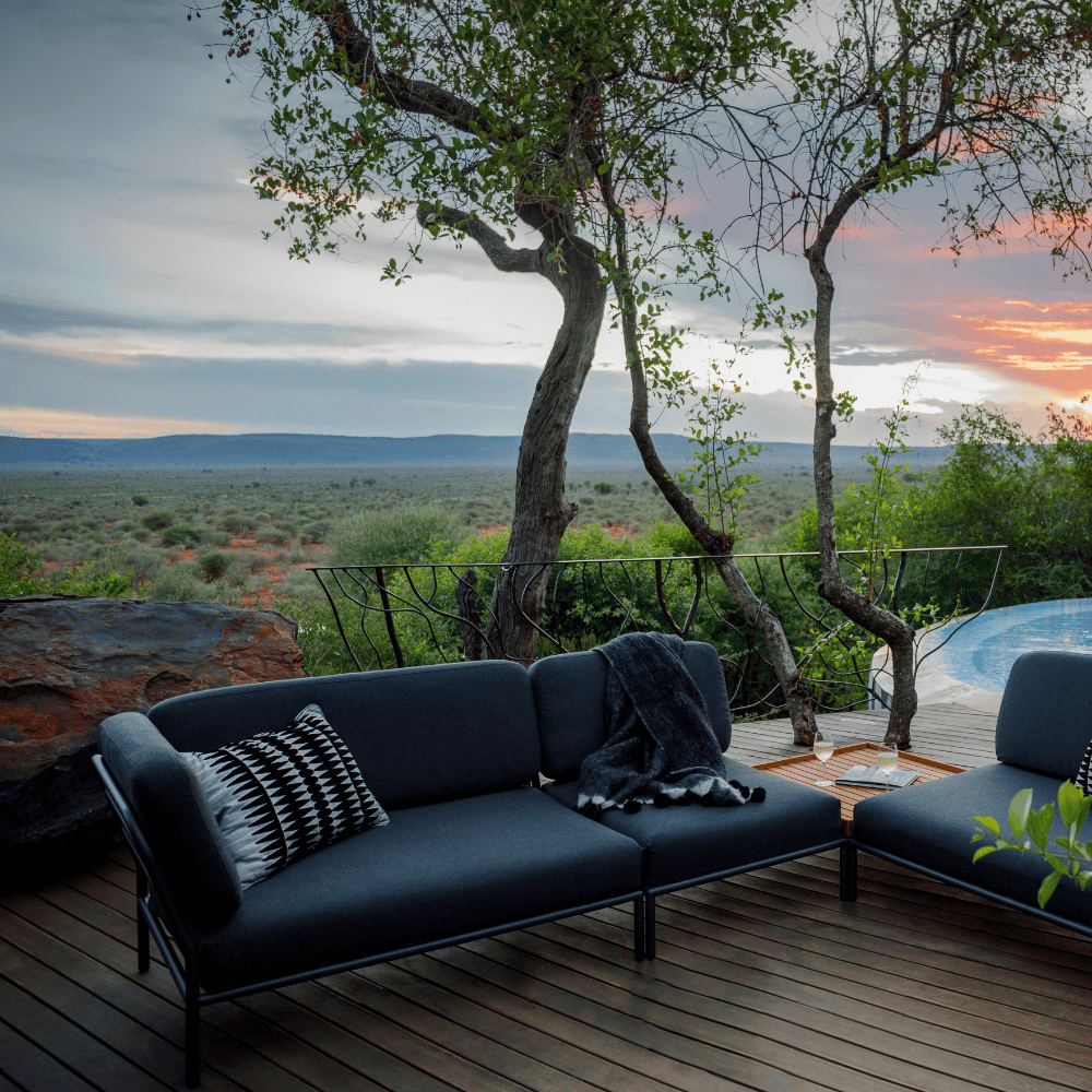 Dark gray left corner lounge sofa with black aluminum frame and dark gray outdoor ottoman set on a wooden deck near the pool