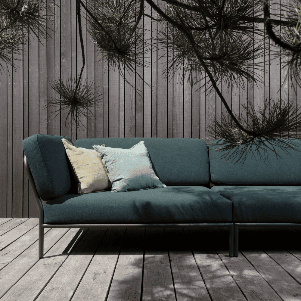 A dark green left corner lounge sofa with dark gray aluminum frame set on a wooden deck patio against wooden wall