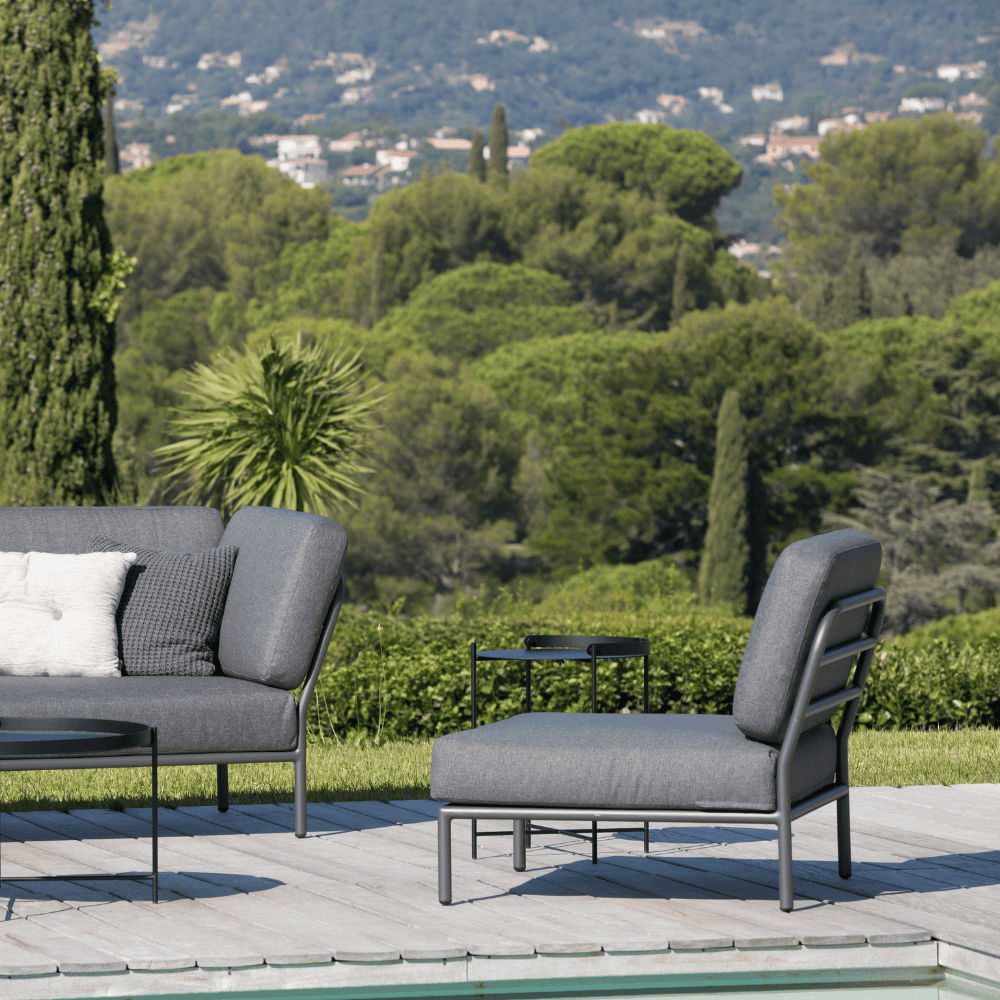 A dark gray outdoor lounge chair with aluminum frame and dark gray outdoor sofa placed on a wooden deck poolside