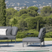 A dark gray outdoor lounge chair with aluminum frame and dark gray outdoor sofa placed on a wooden deck poolside