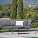 Dark gray right corner lounge sofa with dark gray aluminum frame and round outdoor tray table set on a wooden deck poolside