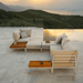 A beige outdoor sectional sofa and wooden outdoor coffee table and side table set beside the pool with view of a green hills