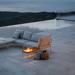 A rectangular wooden outdoor side table and beige outdoor sectional sofa placed beside the pool