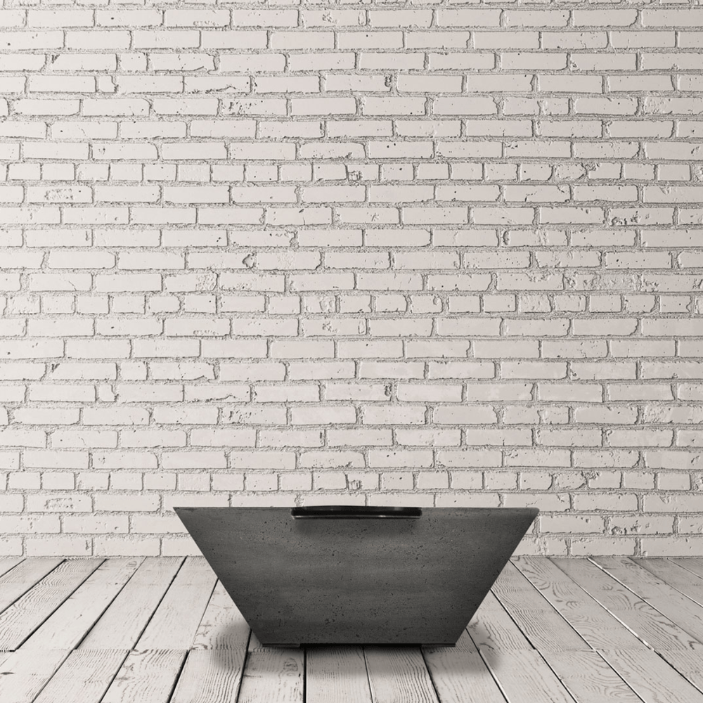 Grey tapered shaped square concrete fire water bowl placed on a wooden deck against white brick wall