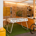 A white outdoor football table with wooden handles placed on a green artificial turf floor in a modern indoor space