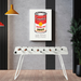 A white outdoor football table set on wooden floor in a modern interior setting with a framed artwork on the wall