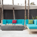 A grey concrete outdoor rectangular fire pit table placed on a modern outdoor setting with turquoise sectional sofa