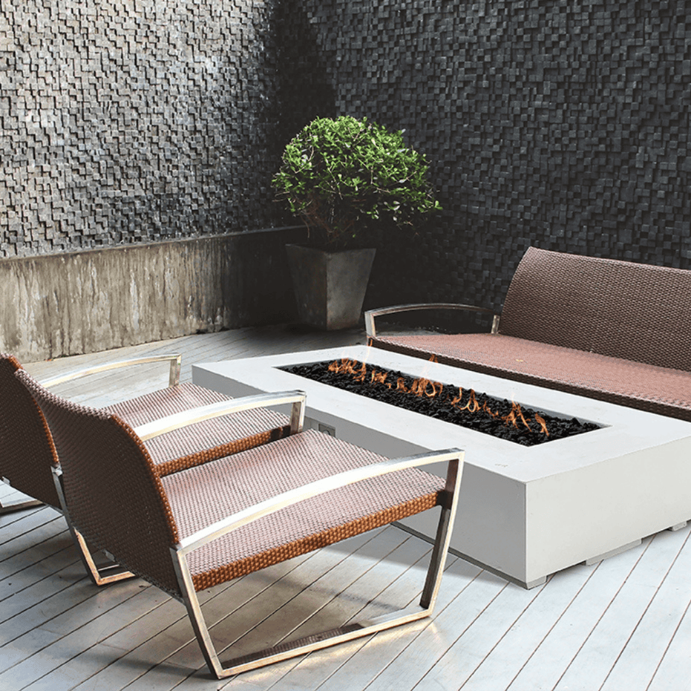 A modern patio featuring a white concrete outdoor rectangular fire pit table surrounded by a brown outdoor chairs and sofa