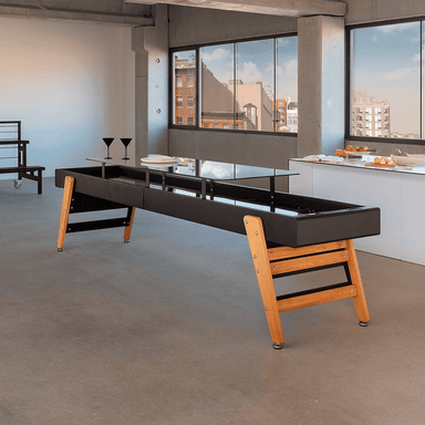 A black track dining outdoor shuffleboard table with wooden legs placed in a modern interior setting with glass windows